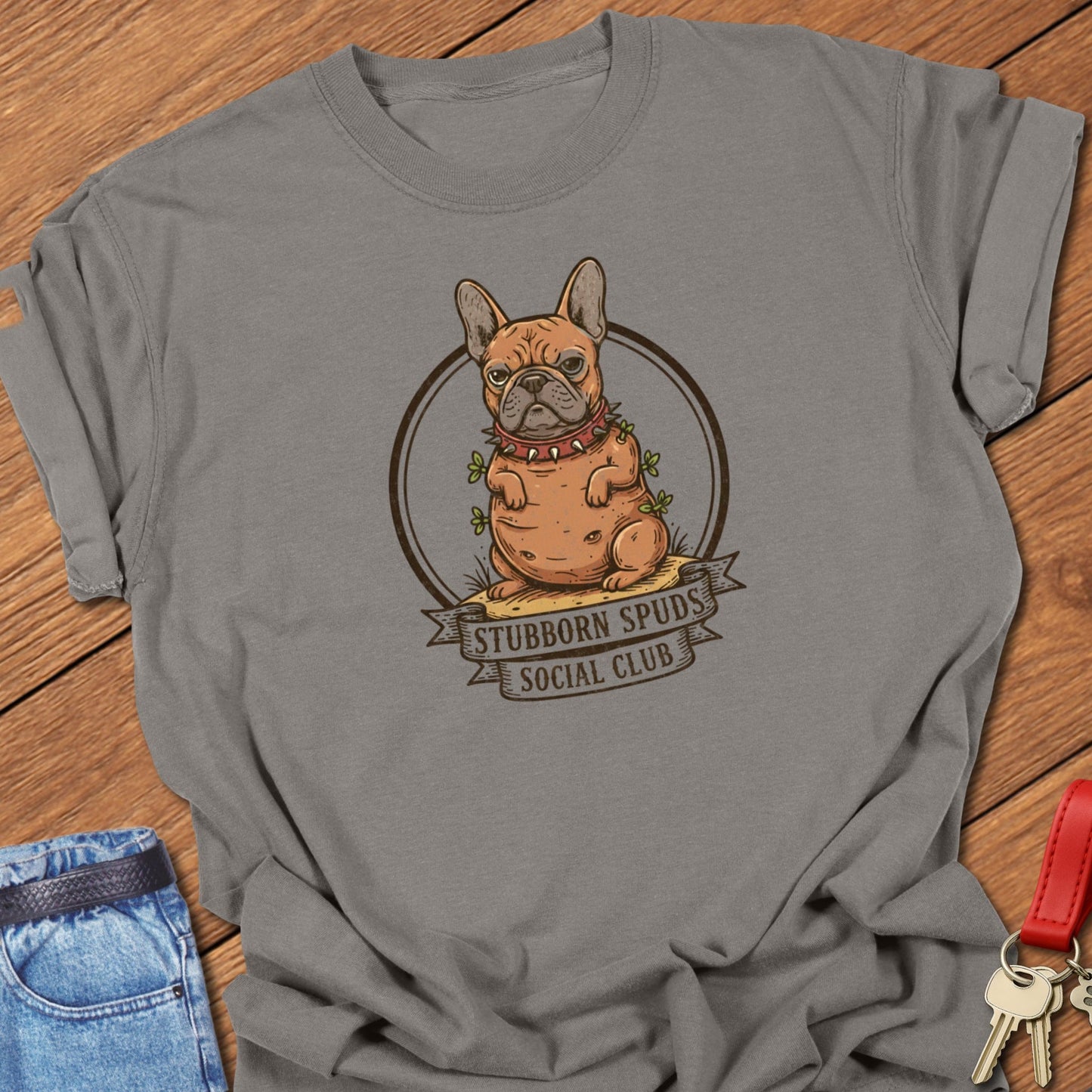 French bulldog illustrated as a potato mascot with “Stubborn Spuds Social Club” banner design printed on grey Comfort Colors t shirt.